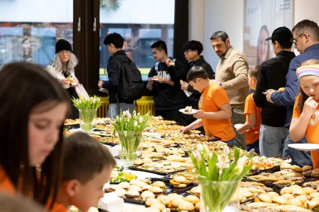 Kinder und Erwachsene bedienen sich am reichhaltigen Buffet mit Fingerfood.